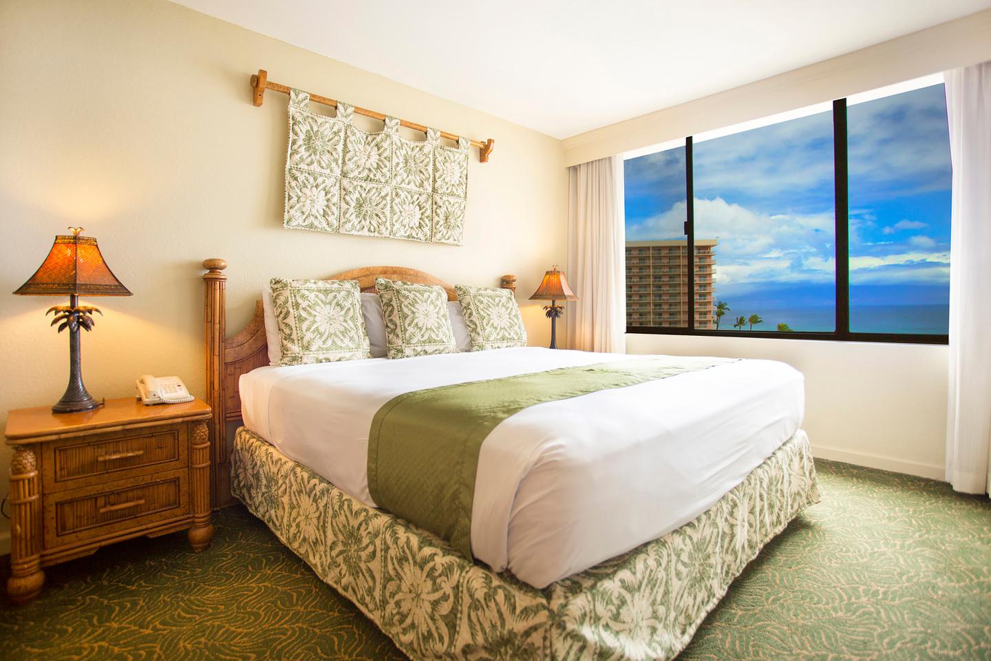 Room with bed, nightstand, lamps, window witj view of ocean