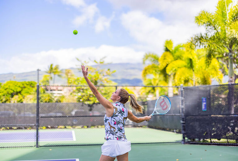 Woman serving tennis on outdoor court. 